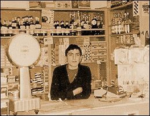 A young man sitting behind a deli counter in a vintage photo
